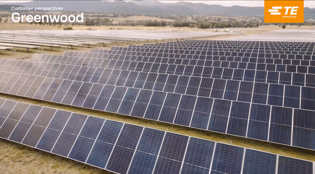 Rows of large solar panels are installed in a field, forming a solar farm with mountains and trees in the background. The sky is overcast. Text at the top left reads Customer Perspectives: Greenwood. TE Connectivity's logo is in the top right.