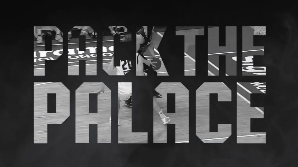 Large, bold, uppercase text reads “PACK THE PALACE” in a blocky font. Inside the text, a greyscale photo of a basketball match is visible, showing players in action on a court. The background is dark with a subtle smoky effect.